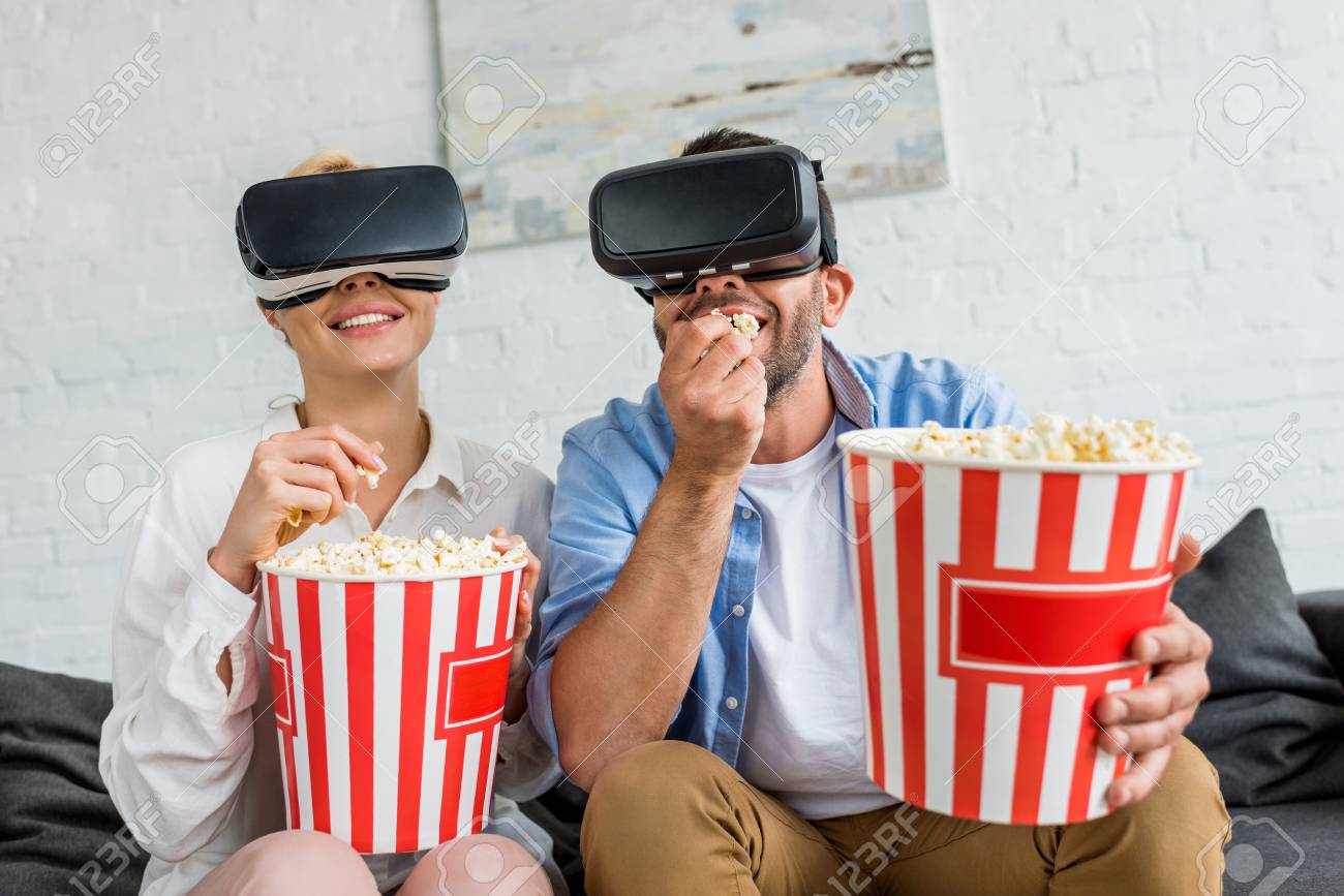106487192-happy-couple-in-virtual-reality-headsets-eating-popcorn-together-at-home.jpg